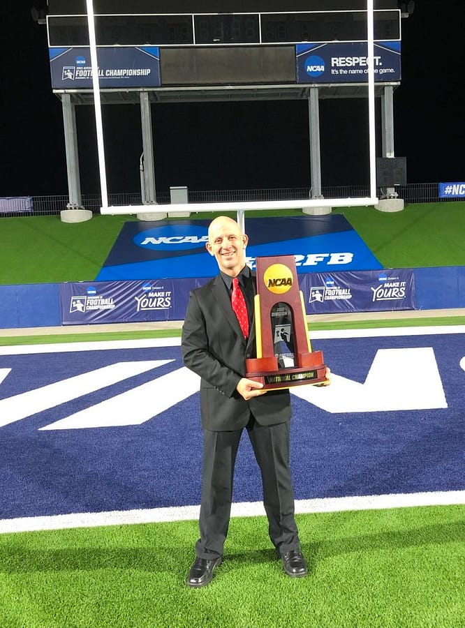 Jeff Rainer shows off the national championship trophy after reffing the game in Dallas, Texas