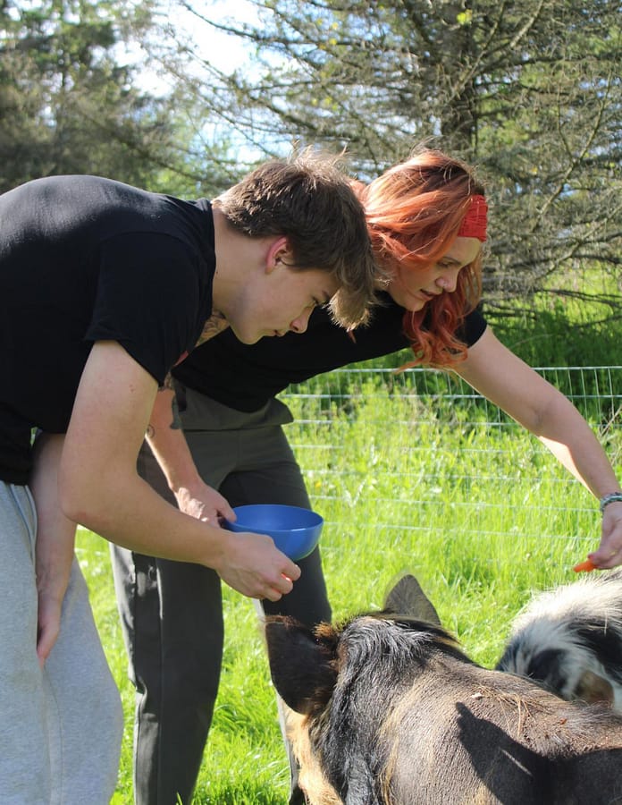 Junior Zak Kegg and tutor Julie Genovese feed their Kunekune pigs, “Boojee” and “Meatlug.”