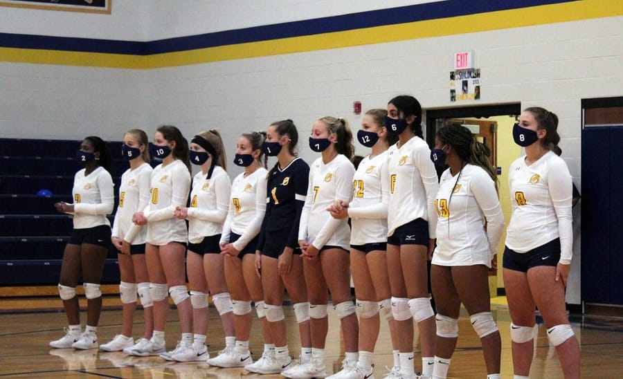 Varsity+players+stand+for+the+national+anthem+wearing+their+team+masks.+The+masks+were+required+any+time+players+were+off+the+court.