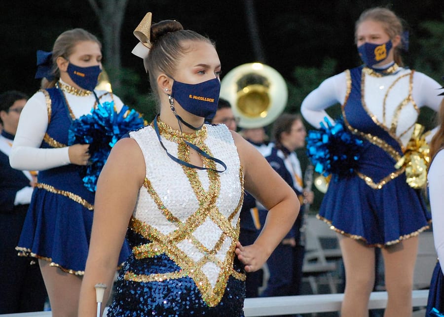 In the front is Senior, Sydney Mccolloch, in the background is Junior, Meghan Epple and Sophomore, Rachel Boger.  These girls are wearing the Streetsboro masks provided to all band members and they are labeled with their names.  These girls wear their masks as they perform for the home halftime show football games.